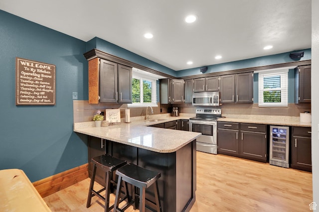 6767 S 1600 W, West Jordan, UT 84084 - kitchen featuring stainless steel appliances, wine cooler, a sink, a peninsula, and a breakfast bar area
