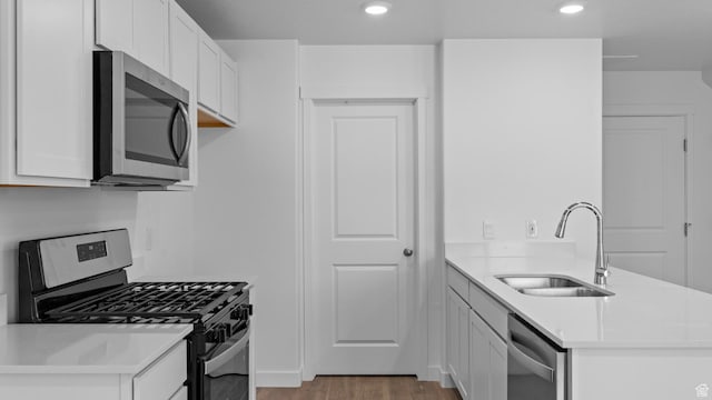 104 N Kelp Ln Unit 2310, Saratoga Springs, UT 84045 - kitchen featuring appliances with stainless steel finishes, a sink, a peninsula, light wood-style flooring, and white cabinetry
