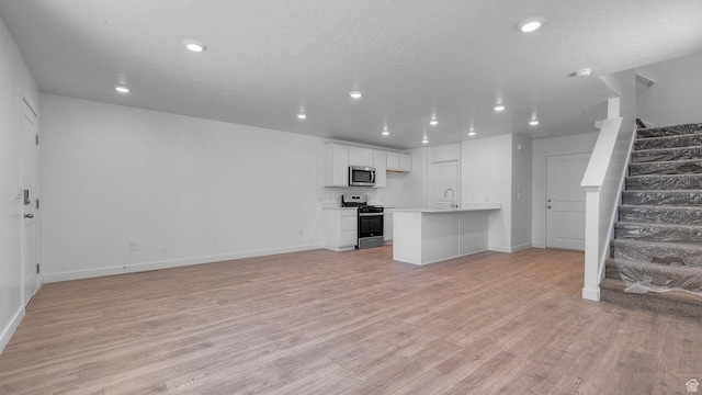 104 N Kelp Ln Unit 2310, Saratoga Springs, UT 84045 - unfurnished living room with stairway, light wood-type flooring, recessed lighting, baseboards, and a sink