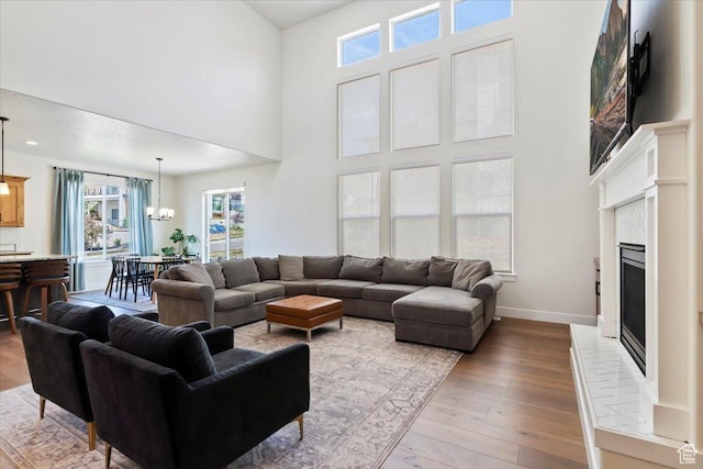 1046 W Seasons View Ct, Lehi, UT 84043 - living room with a chandelier, a towering ceiling, a fireplace with raised hearth, hardwood / wood-style flooring, and baseboards