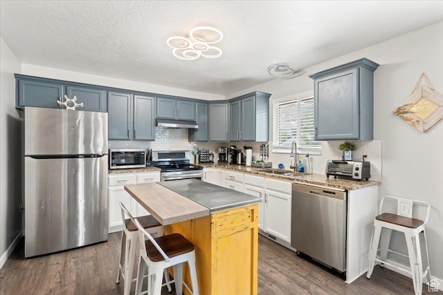 7265 N Ute Dr, Eagle Mountain, UT 84005 - kitchen featuring appliances with stainless steel finishes, a sink, under cabinet range hood, and decorative backsplash