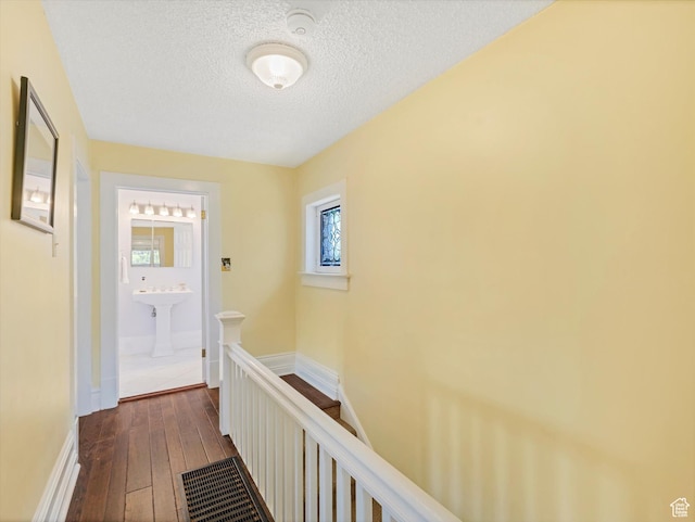 218 E Fifth Ave, Salt Lake City, UT 84103 - hallway featuring an upstairs landing, a textured ceiling, dark wood-type flooring, a sink, and baseboards