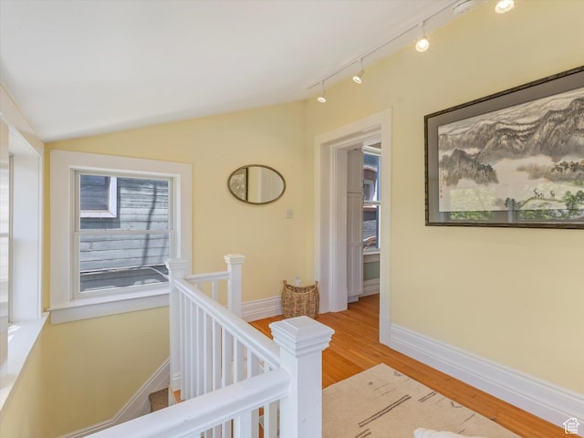 218 E Fifth Ave, Salt Lake City, UT 84103 - hall with an upstairs landing, wood finished floors, vaulted ceiling, rail lighting, and baseboards