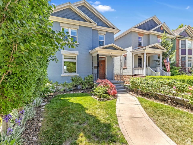 218 E Fifth Ave, Salt Lake City, UT 84103 - view of front of home featuring brick siding, a front lawn, and a porch