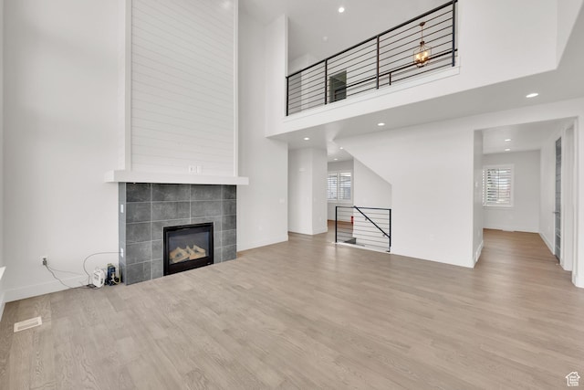 2279 E Ravine Rock Way, Draper, UT 84020 - unfurnished living room with plenty of natural light, wood finished floors, a tiled fireplace, recessed lighting, and baseboards