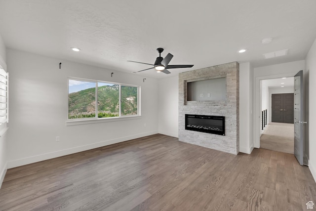 2279 E Ravine Rock Way, Draper, UT 84020 - unfurnished living room with a stone fireplace, baseboards, a ceiling fan, wood finished floors, and recessed lighting