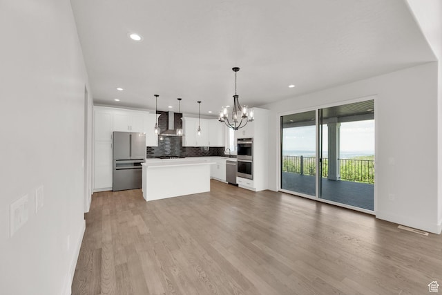 2279 E Ravine Rock Way, Draper, UT 84020 - kitchen featuring appliances with stainless steel finishes, wall chimney exhaust hood, a chandelier, tasteful backsplash, and a center island