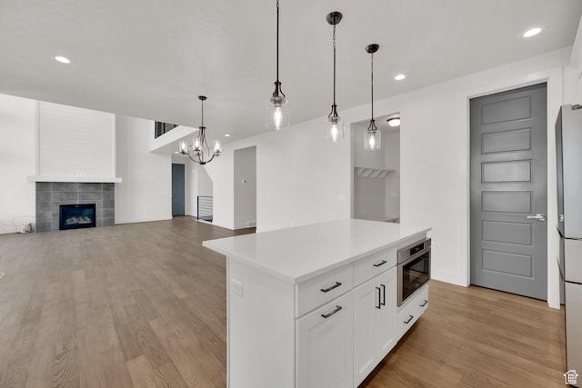 2279 E Ravine Rock Way, Draper, UT 84020 - kitchen with light wood-style flooring, a fireplace, light countertops, white cabinetry, and recessed lighting