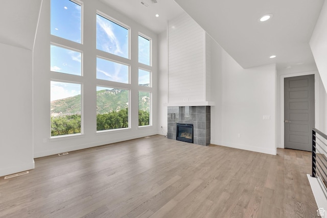 2279 E Ravine Rock Way, Draper, UT 84020 - unfurnished living room with a tiled fireplace, plenty of natural light, a high ceiling, light wood-type flooring, and baseboards