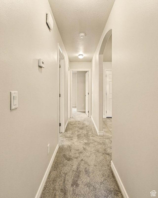 1447 S Southern View Dr, Cedar City, UT 84720 - corridor featuring light carpet, a textured ceiling, baseboards, and arched walkways
