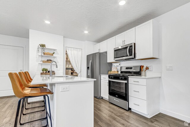 1323 S 3540 E, Spanish Fork, UT 84660 - kitchen featuring appliances with stainless steel finishes, light wood-style flooring, light countertops, a breakfast bar area, and white cabinetry