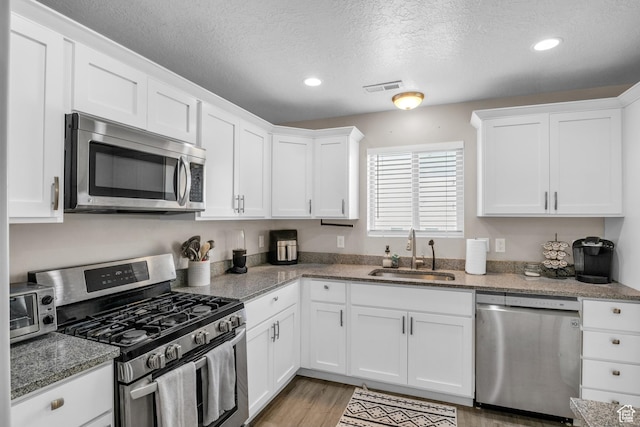 1113 E 870 N, Spanish Fork, UT 84660 - kitchen featuring appliances with stainless steel finishes, white cabinets, a textured ceiling, recessed lighting, and light wood-type flooring