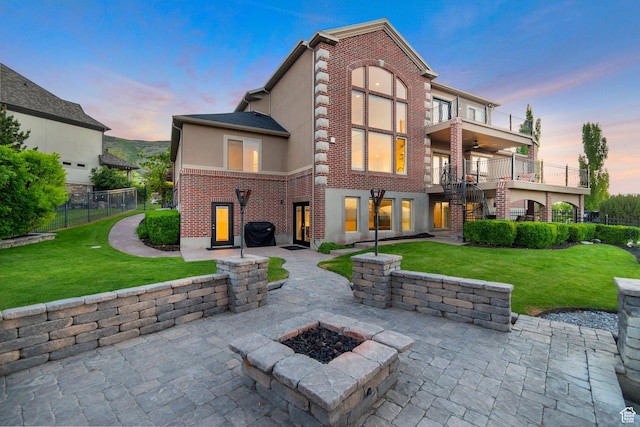 14709 S Cedar Knoll Cir, Herriman, UT 84096 - back of house at dusk featuring a patio, a balcony, stairs, stucco siding, and a fire pit