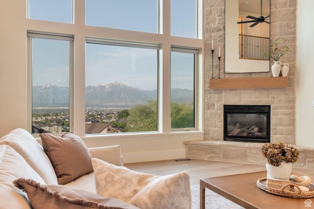 14709 S Cedar Knoll Cir, Herriman, UT 84096 - living room with wood finished floors, a mountain view, a towering ceiling, a stone fireplace, and a ceiling fan