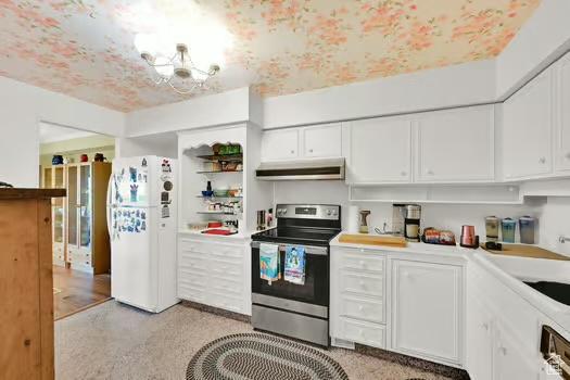 1785 29th St Unit 504, Ogden, UT 84403 - kitchen with electric range, freestanding refrigerator, under cabinet range hood, white cabinets, and a chandelier