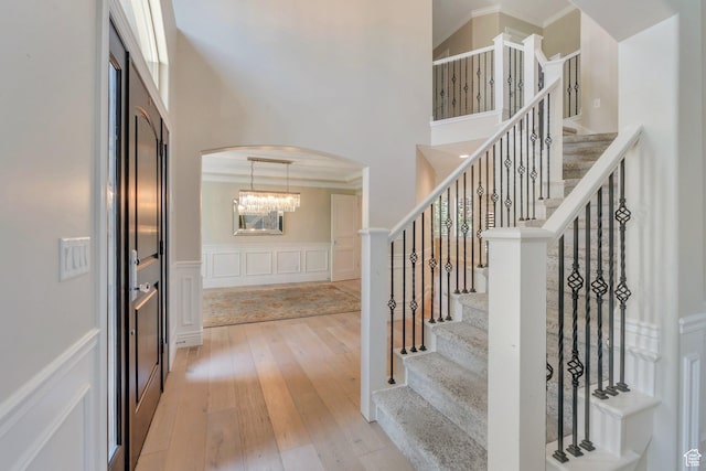 719 E Hampton Ct N, Alpine, UT 84004 - entryway featuring arched walkways, a towering ceiling, light wood-style flooring, stairs, and a decorative wall
