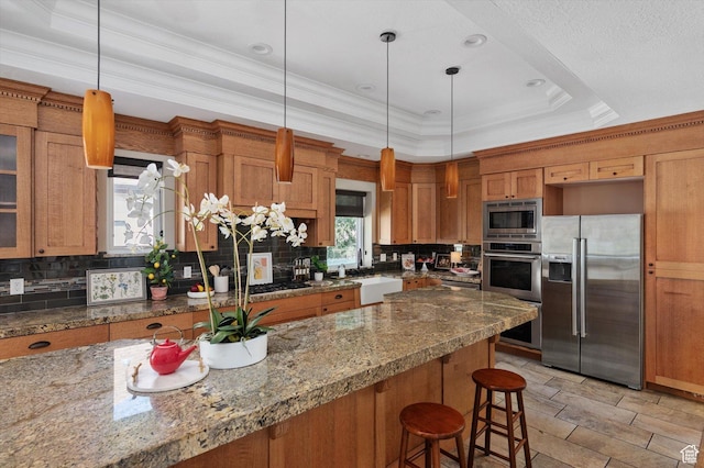 521 E 900 S, Salt Lake City, UT 84105 - kitchen with stainless steel appliances, a raised ceiling, a kitchen breakfast bar, brown cabinetry, and crown molding