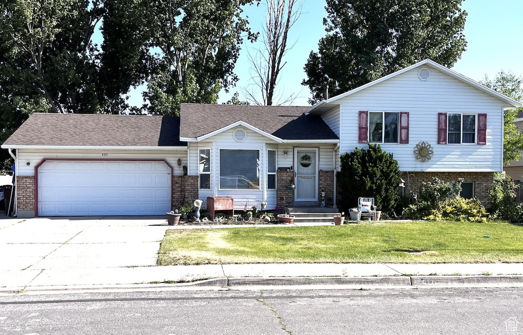 497 W 2280 N, Lehi, UT 84043 - tri-level home with a garage, brick siding, concrete driveway, and a front lawn