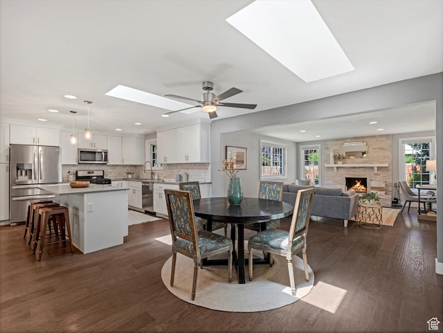 1555 E Fieldcrest Ln, Holladay, UT 84117 - dining room featuring a skylight, healthy amount of natural light, a stone fireplace, dark wood-style flooring, and recessed lighting