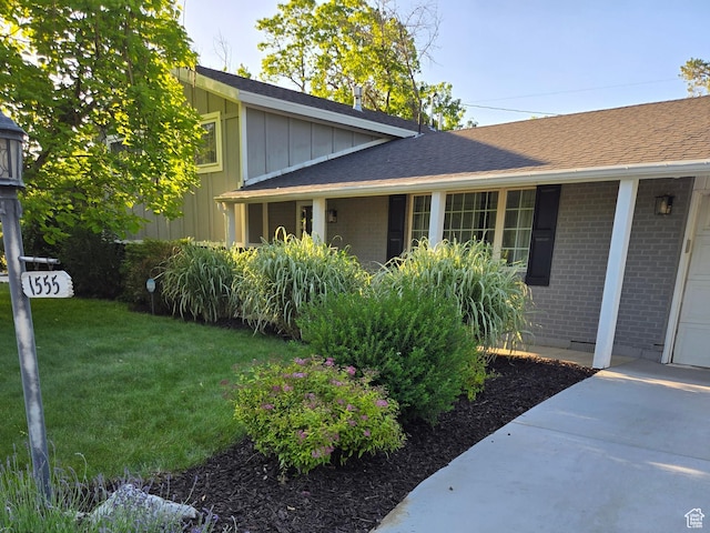 1555 E Fieldcrest Ln, Holladay, UT 84117 - view of side of property with brick siding, board and batten siding, a yard, and a shingled roof