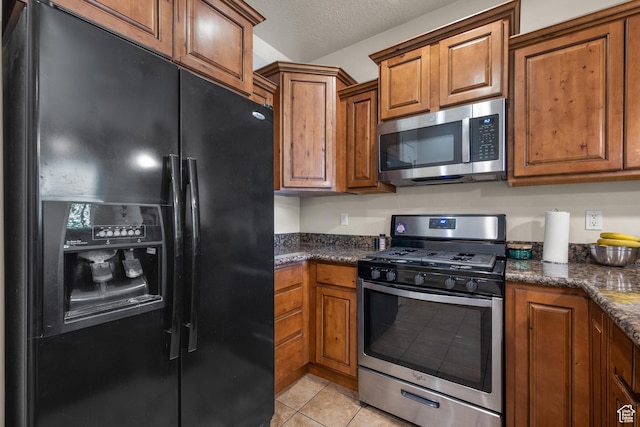 84 S 1630 W, Pleasant Grove, UT 84062 - kitchen featuring stainless steel appliances, brown cabinets, light tile patterned flooring, a textured ceiling, and dark stone counters