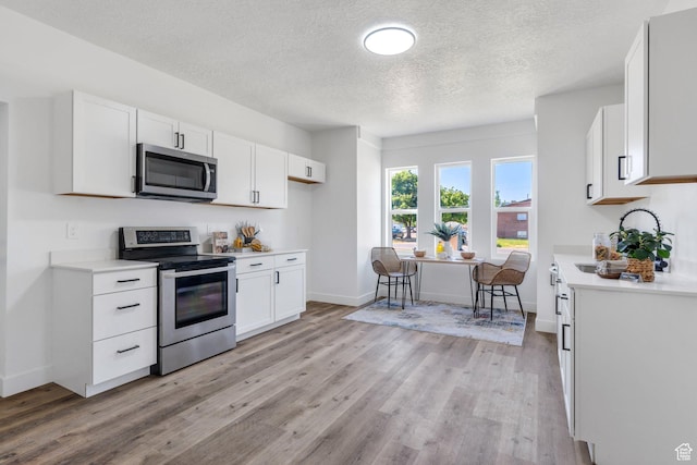 195 E 200 S, Nephi, UT 84648 - kitchen with appliances with stainless steel finishes, light countertops, light wood finished floors, a textured ceiling, and white cabinets