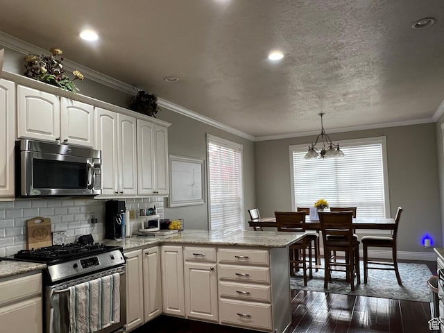 1107 E 1625 N, North Logan, UT 84341 - kitchen with stainless steel appliances, dark wood finished floors, a peninsula, backsplash, and white cabinets