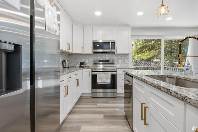 8485 S 1575 E, Sandy, UT 84093 - kitchen featuring appliances with stainless steel finishes, a sink, white cabinetry, light wood finished floors, and tasteful backsplash