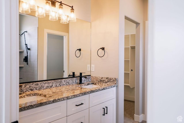 583 N Staci Dr, Hurricane, UT 84737 - bathroom featuring double vanity, a walk in closet, a chandelier, tiled shower, and baseboards