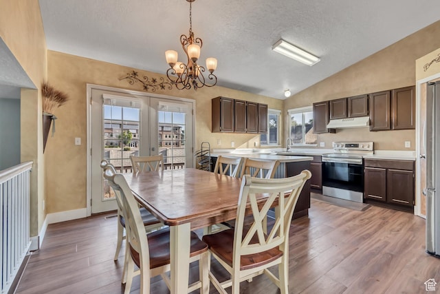 8465 S 1670 W, West Jordan, UT 84088 - dining space with vaulted ceiling, a textured ceiling, a chandelier, light wood-style floors, and baseboards