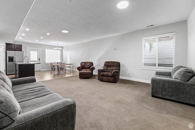 3946 W Birmingham Cir S, Jordan, UT 84009 - carpeted living room featuring recessed lighting, baseboards, a chandelier, a textured ceiling, and a sink