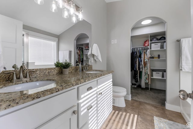 3946 W Birmingham Cir S, Jordan, UT 84009 - bathroom featuring a walk in closet, double vanity, toilet, vaulted ceiling, and baseboards