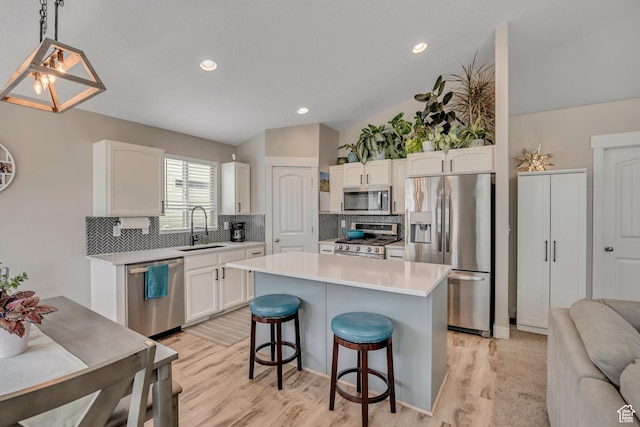 8831 W Digger Ln S, Magna, UT 84044 - kitchen with appliances with stainless steel finishes, white cabinets, backsplash, a kitchen bar, and a sink