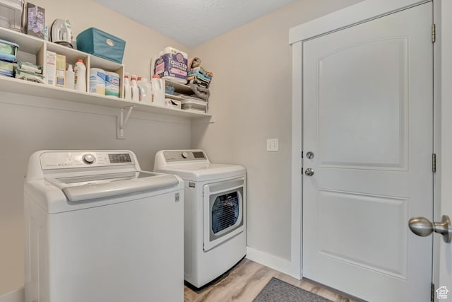 8831 W Digger Ln S, Magna, UT 84044 - washroom with washer and clothes dryer, light wood-type flooring, baseboards, and a textured ceiling