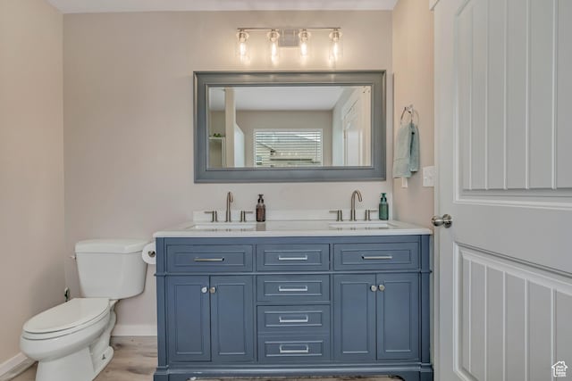 8831 W Digger Ln S, Magna, UT 84044 - bathroom featuring double vanity, toilet, baseboards, and wood finished floors