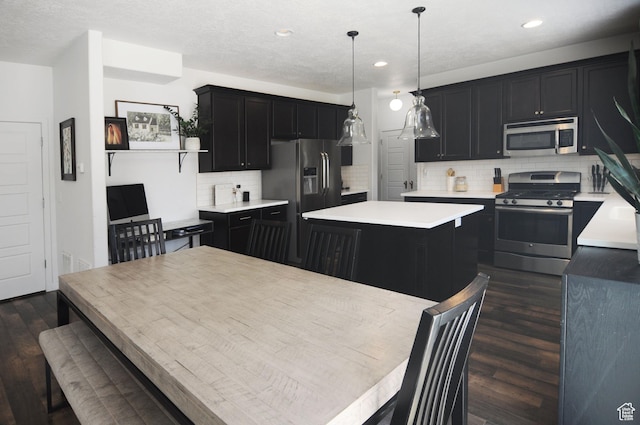 3639 S Clearwater Way, Syracuse, UT 84075 - kitchen featuring stainless steel appliances, dark cabinetry, dark wood finished floors, a center island, and light countertops