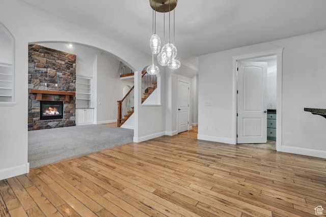 1498 W Mule Train Dr, Bluffdale, UT 84065 - unfurnished living room with stairs, light wood finished floors, arched walkways, built in features, and baseboards
