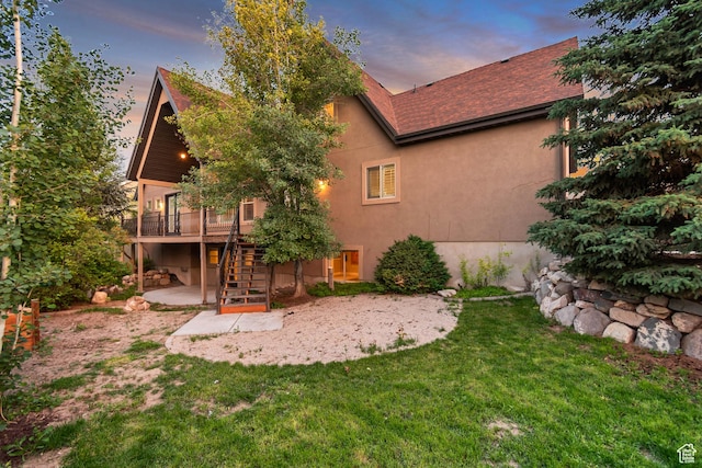 1498 W Mule Train Dr, Bluffdale, UT 84065 - back of house at dusk featuring stairway, a patio, a wooden deck, stucco siding, and a lawn
