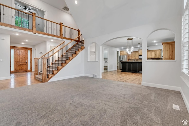 1498 W Mule Train Dr, Bluffdale, UT 84065 - unfurnished living room with light colored carpet, a towering ceiling, stairway, baseboards, and recessed lighting