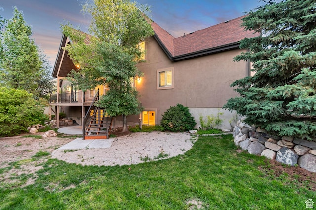 1498 W Mule Train Dr, Bluffdale, UT 84065 - back of property at dusk featuring stairway, stucco siding, a patio, a wooden deck, and a lawn
