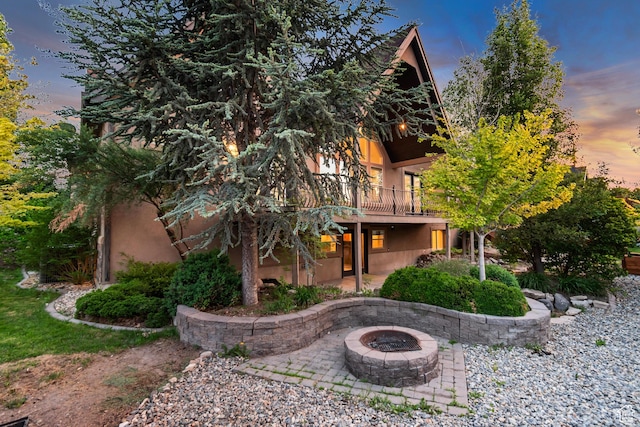 1498 W Mule Train Dr, Bluffdale, UT 84065 - back of house at dusk with a patio, a fire pit, stucco siding, and a balcony