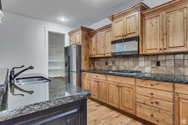 1498 W Mule Train Dr, Bluffdale, UT 84065 - kitchen with stainless steel appliances, a sink, light wood finished floors, dark stone counters, and decorative backsplash