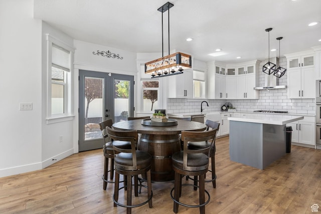 12612 S Starlite Hill Ln W, Herriman, UT 84096 - kitchen with a kitchen island, tasteful backsplash, light wood finished floors, glass insert cabinets, and gas cooktop
