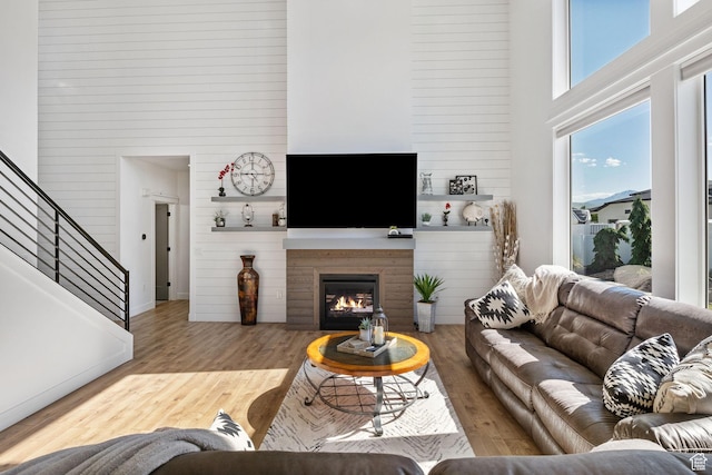 12612 S Starlite Hill Ln W, Herriman, UT 84096 - living room featuring a high ceiling, a lit fireplace, stairs, and wood finished floors