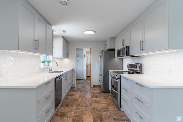 983 Westwood Dr, Pleasant View, UT 84414 - kitchen featuring stainless steel appliances, a sink, stone finish flooring, decorative backsplash, and light countertops