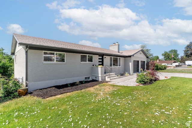 983 Westwood Dr, Pleasant View, UT 84414 - back of house featuring an attached garage, concrete driveway, brick siding, a chimney, and a yard