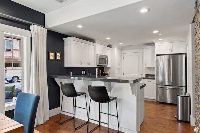 760 W Holliday Dr, Kamas, UT 84036 - kitchen featuring appliances with stainless steel finishes, a peninsula, white cabinetry, a kitchen breakfast bar, and recessed lighting