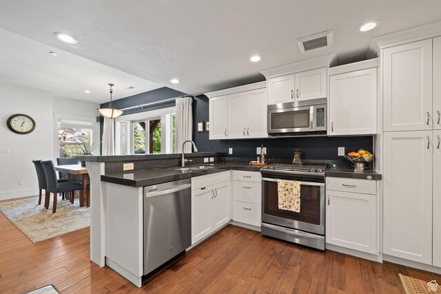 760 W Holliday Dr, Kamas, UT 84036 - kitchen with appliances with stainless steel finishes, a sink, a peninsula, white cabinets, and dark countertops