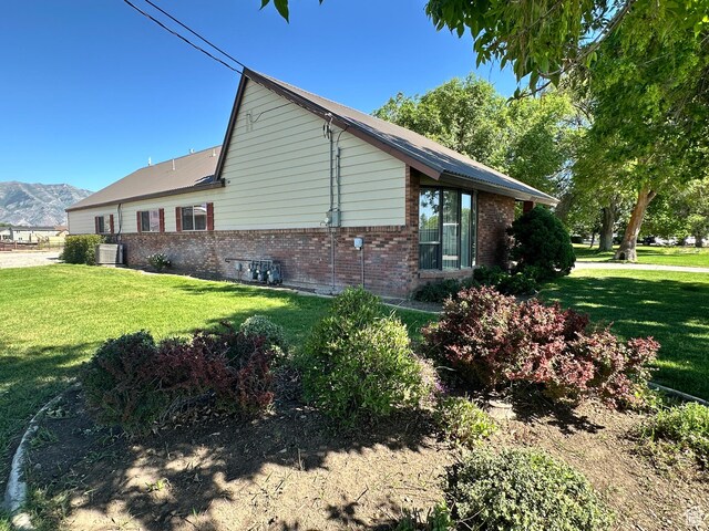 102 S 1000 W, Tremonton, UT 84337 - view of side of home with brick siding, a yard, a mountain view, and cooling unit