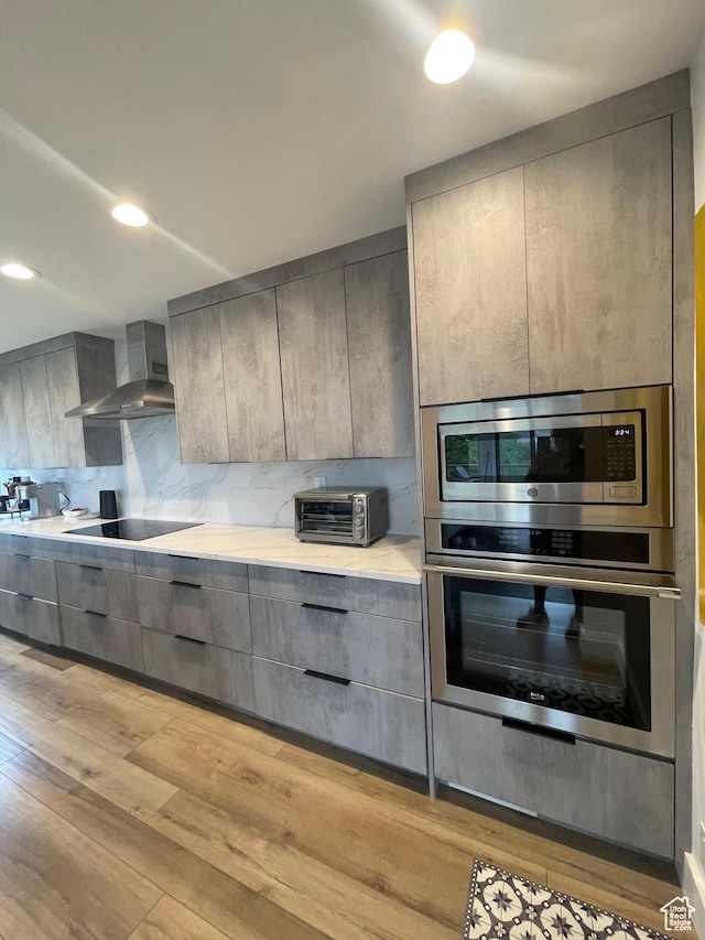 3599 E Oakview Dr, Millcreek, UT 84124 - kitchen featuring wall chimney range hood, gray cabinetry, appliances with stainless steel finishes, and light wood-type flooring